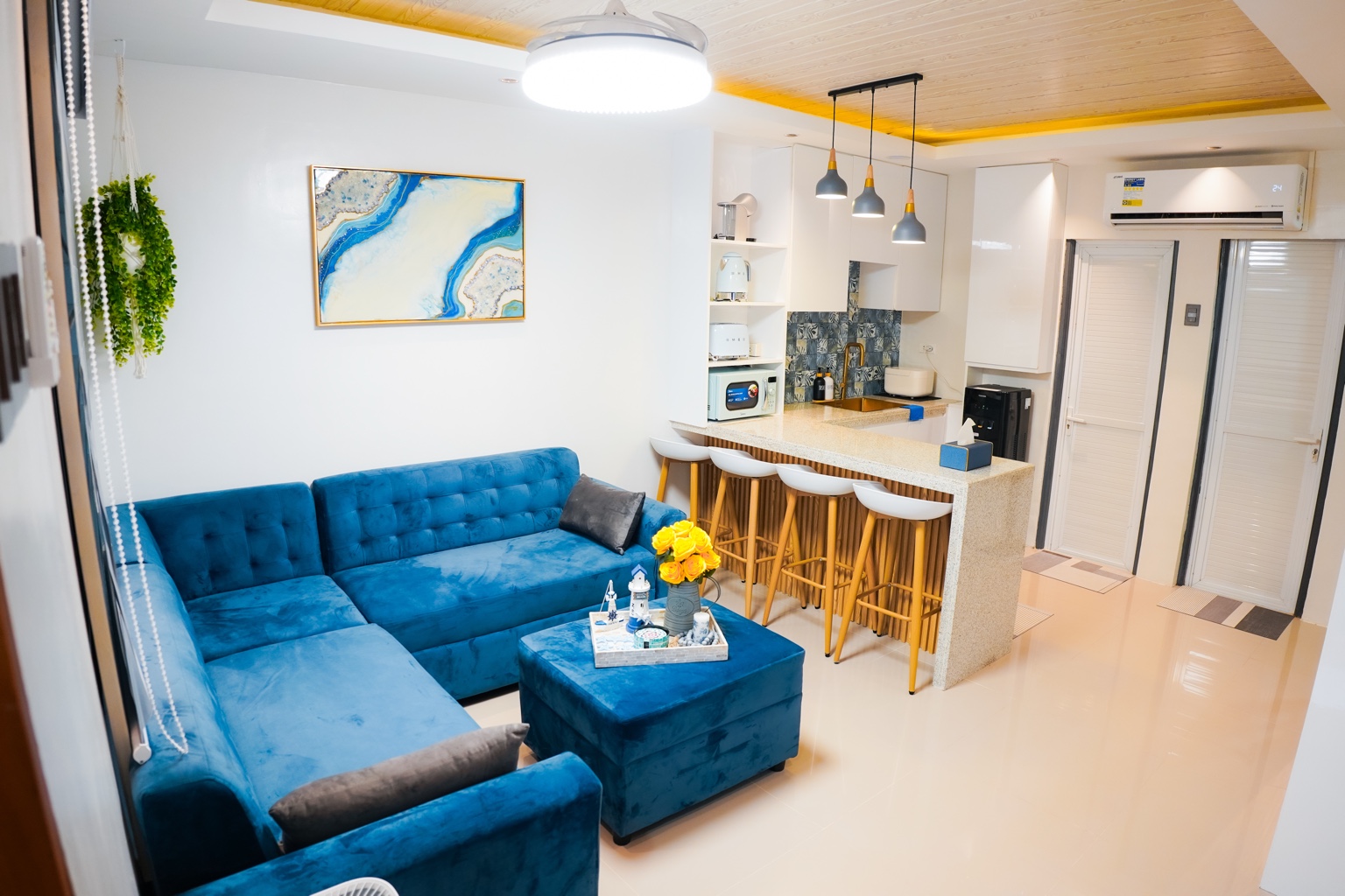 Casa Lucia’s bright living room with blue sofa, resin art and open kitchen